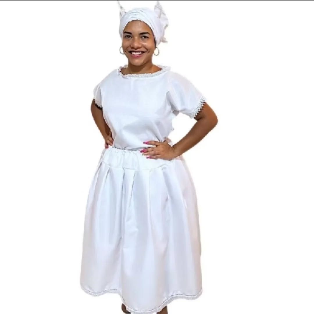 Mulher sorrindo com ojá branco, blusa de renda e saia branca de axé